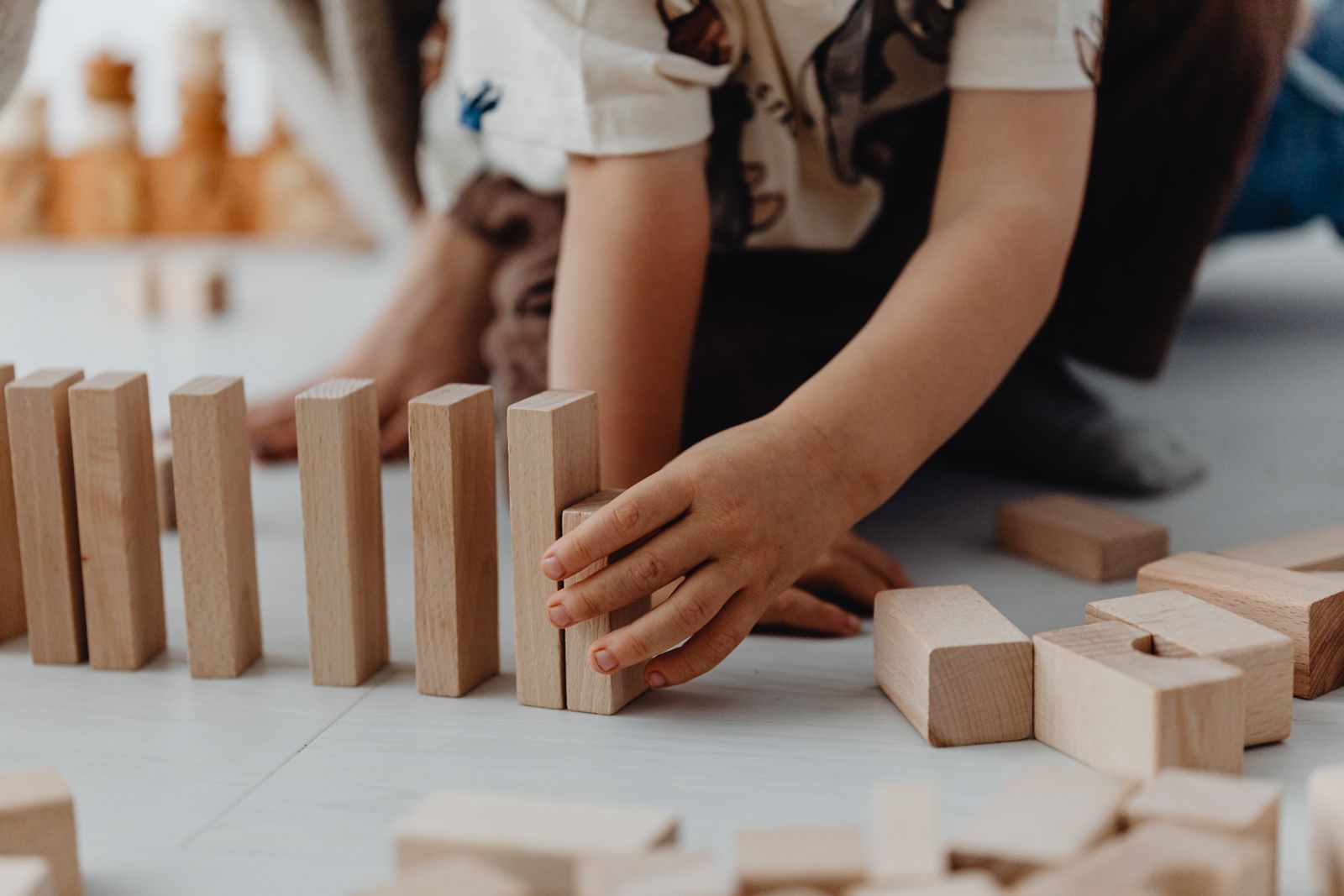 Hands standing wooden blocks on end in a long row
